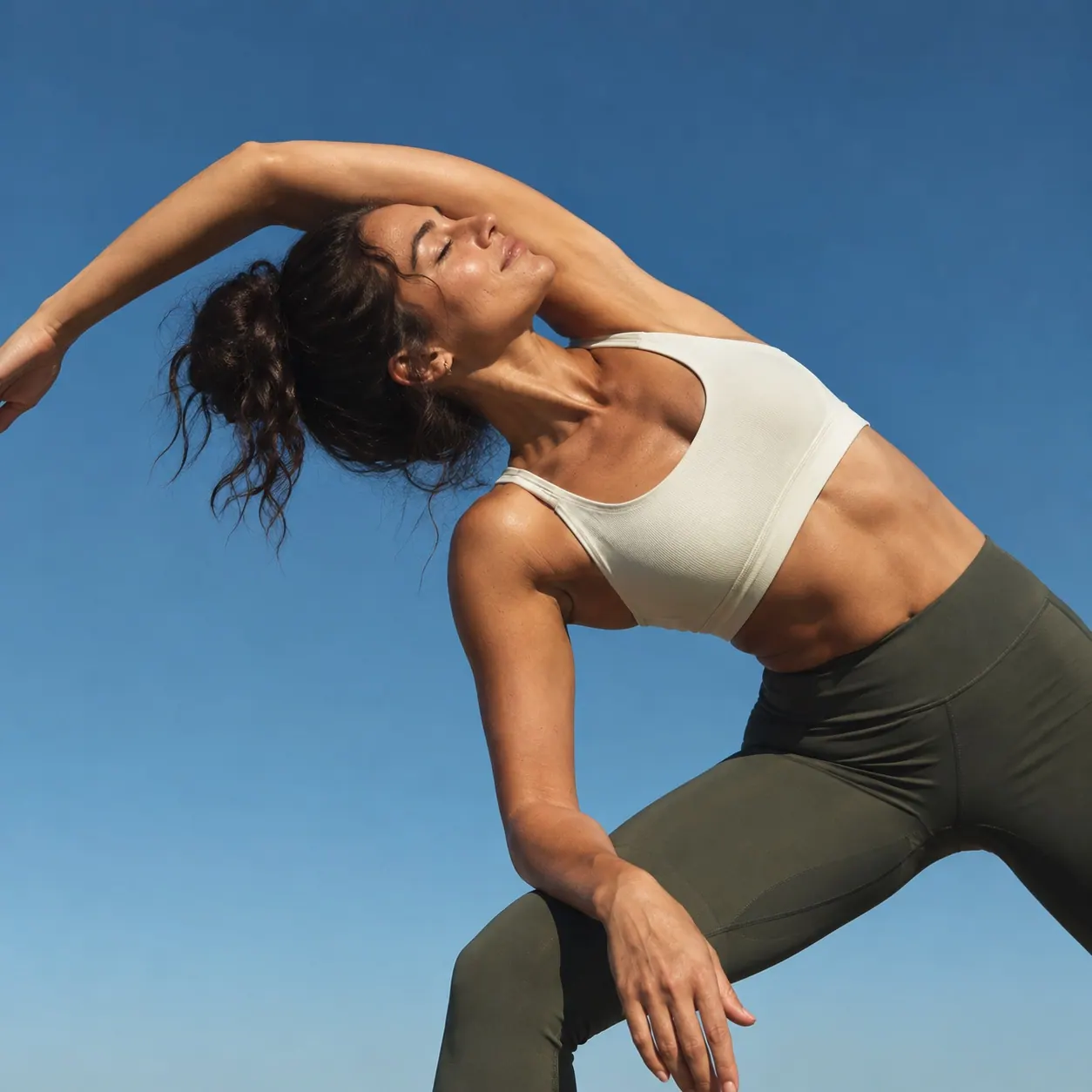 A woman stretching under a clear blue sky